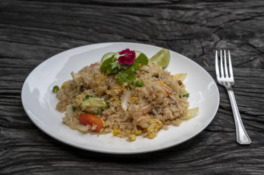 Eski bir ahşap masada beyaz bir tabak karides ve sebze ile Kızarmış pirinç, yakın . Tay yemekleri , Tay mutfağı