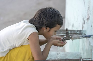 Susamış Hintli kız Portresi Rishikesh, Hindistan sokakta açık musluk su içecekler