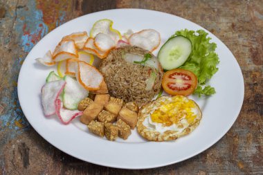 Yerel kafede eski ahşap masada sebze, pirinç cips, peynir tofu ve kızarmış yumurta ile kızarmış pirinç, Endonezya mutfağı yakın. Bali Kahvaltı, Endonezya