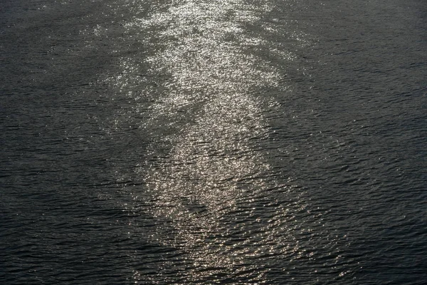 Reflejo del atardecer brilla en diminutas olas de agua de mar — Foto de Stock