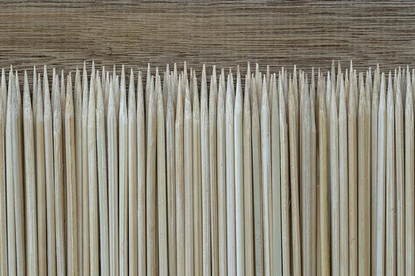 Pile of wooden sticks or bamboo skewers used to hold pieces of food together on wood background — Stock Photo, Image