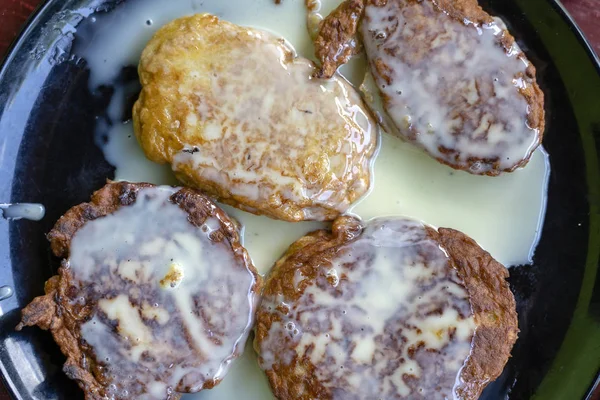 Banana fritters med kondenserad mjölk i svart plåt till frukost. Läcker efterrätt, närbild — Stockfoto