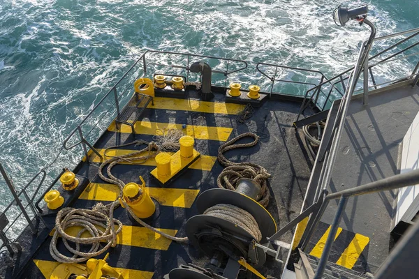 The deck of the ferry boat along with the a thick mooring rope and blue sea water wave, Thailand. Close up