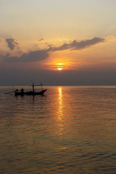 Silhuet af en mand på en båd under solnedgang på havet . - Stock-foto