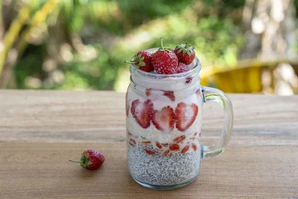 Pudín de chía con leche de almendras con fresas rojas frescas, bayas de goji y copos de avena en una taza de tarro de vidrio. Desayuno crudo vegano. Semillas de chía y fruta fresca cortada y postre de bayas — Foto de Stock