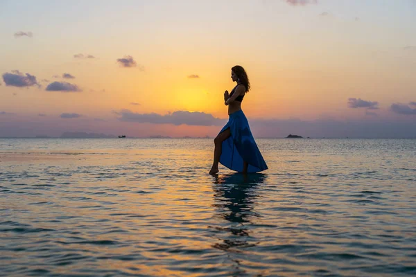 Junges Schönheitsmädchen, das am tropischen Strand auf dem Meerwasser der Paradiesinsel bei Sonnenuntergang tanzt. Sommerkonzept. Urlaubsreise. — Stockfoto