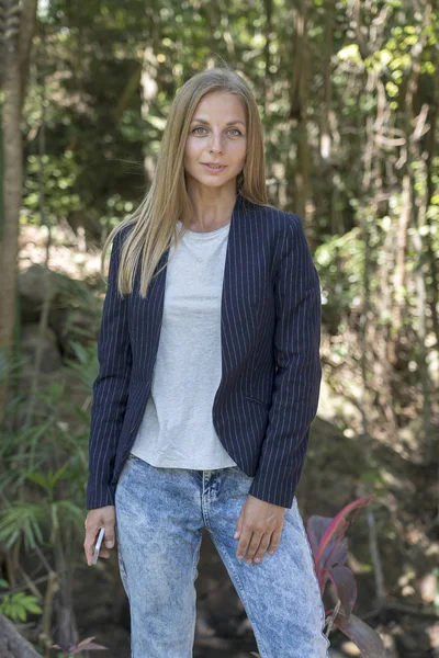 Hermosa chica rubia caucásica en un traje de negocios en el fondo de la naturaleza. Un retrato de una joven mujer de negocios en un jardín tropical, Tailandia — Foto de Stock