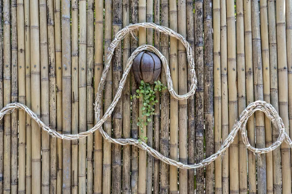 Decorated bamboo wall with a rope and a coconut flower pot on a tropical beach in Thailand — Stock Photo, Image