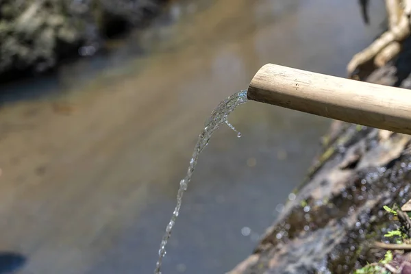 竹管からの水は、インドネシアの島バリ島ウブドの川に流れ込みます。クローズ アップ — ストック写真