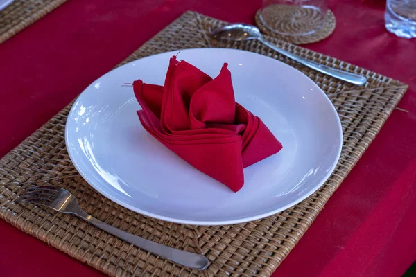 Restoranda çatal, kaşık, beyaz plaka ve kırmızı peçete ile zarif masa ayarı. Düzenlenmiş gümüş ve peçeteler ile güzel yemek masası seti — Stok fotoğraf
