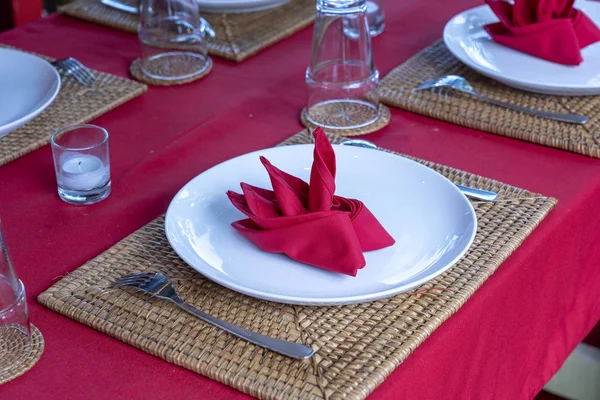 Elegante tafel setting met vork, lepel, witte plaat en rode servet in restaurant. Mooie eettafel set met gearrangeerd zilverwerk en servetten — Stockfoto