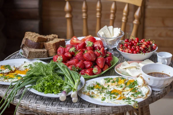 Вкусный и здоровый завтрак на столе, крупным планом. Жареные яйца, хлеб, зелень, овощи, ягоды и сыр на завтрак — стоковое фото
