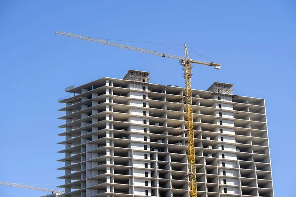 Construcción de un edificio de gran altura con grúa. La grúa de construcción y el edificio contra el cielo azul . — Foto de Stock
