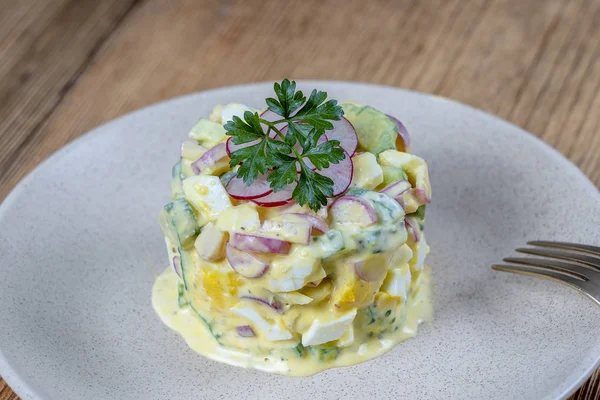 Heerlijke salade met komkommer, radijs en ei met roomsaus in een bord op houten achtergrond. Gezond eten, close-up — Stockfoto