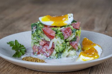 Brokoli, domates, soğan ve ahşap arka plan tabaktabakta krema sos lu haşlanmış yumurta ile lezzetli salata. Sağlıklı gıda