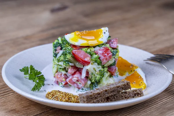 Delicious saláta brokkolival, paradicsommal, hagymával és főtt tojással, tejszínes mártással, fából készült háttérrel. Egészséges táplálkozás — Stock Fotó