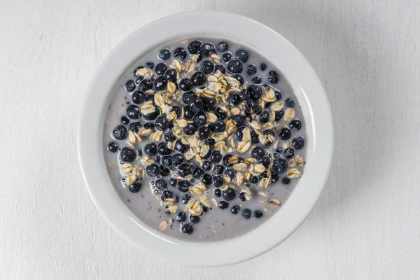 Haferflocken mit frischen Blaubeeren, Mandelmilch und Honig zum Frühstück im Teller auf Holzgrund. rustikaler Stil. Ansicht von oben. — Stockfoto