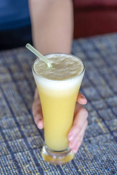 Mulher mão segurando um copo de suco de abacaxi fresco, close-up — Fotografia de Stock