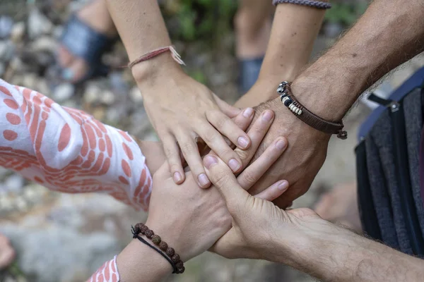 Many hands getting together in the center of a circle. Close up outdoor shot