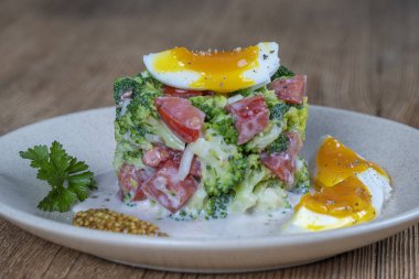 Brokoli, domates, soğan ve ahşap arka plan tabaktabakta krema sos lu haşlanmış yumurta ile lezzetli salata. Sağlıklı gıda