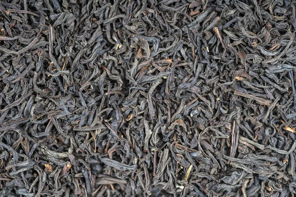 El té negro deja el fondo. Texturas de alimentos abstractos. De cerca. — Foto de Stock