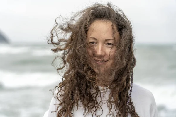 Mujer joven cerca del mar agitando su cabeza hacia un lado y agitando el pelo en el viento — Foto de Stock