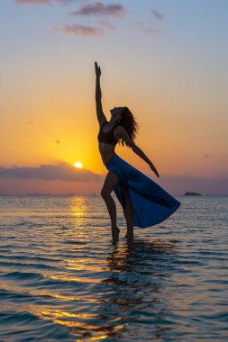 Gün batımında cennet adasında deniz suyunda tropikal plajda dans genç güzellik kız. Yaz konsepti. Tatil seyahati.