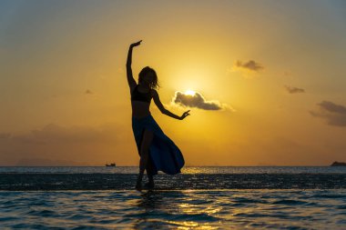 Gün batımında cennet adasında deniz suyunda tropikal plajda dans genç güzellik kız. Yaz konsepti. Tatil seyahati.