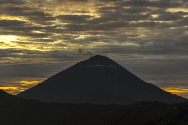 Gün doğumunda volkan dağlarının silhoutte ile bulutlu manzara. Bali, Endonezya