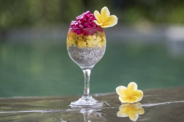 Arka plandaki yüzme havuzu su kahvaltıda puding bir bardak kırmızı dragon meyve ve beyaz Yoğurtlu Chia tohum. Sağlıklı beslenme kavramı.