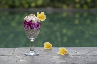 Arka plandaki yüzme havuzu su kahvaltıda puding bir bardak kırmızı dragon meyve ve beyaz Yoğurtlu Chia tohum. Sağlıklı beslenme kavramı.