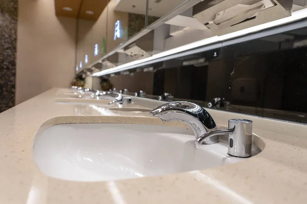 Faucets with washbasin in public restroom, close up — Stock Photo, Image