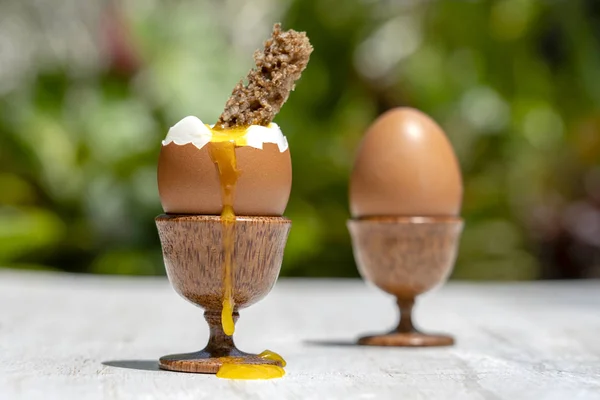 Weich gekochtes Ei in Eierbecher mit Toastbrot auf weißem Holztisch im Hintergrund der Natur, Nahaufnahme — Stockfoto