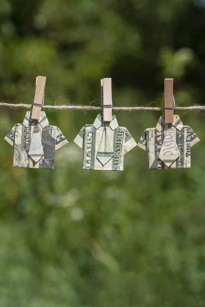 Орігамі сорочка з доларової банкноти на висячому зеленому фоні природи. доларові купюри, що висять на мотузці. крупним планом — стокове фото