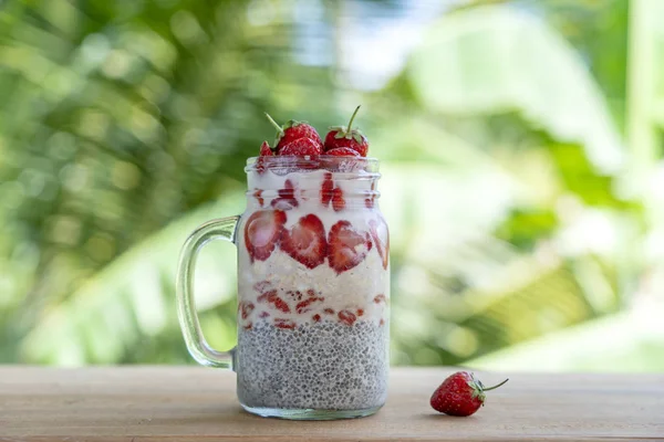 Almond milk chia pudding with fresh red strawberries, goji berries and oat flakes in a glass jar mug. Vegan raw breakfast. Chia seeds and fresh cut fruits and berries dessert — Stock Photo, Image