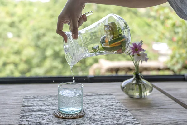 Un camarero en un restaurante vierte agua de frutas de una jarra en un vaso — Foto de Stock