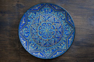 Mavi ve altın rengi nde dekoratif seramik plaka, ahşap arka plan üzerine boyanmış plaka, closeup. Akrilik boyalar ile boyanmış dekoratif porselen plaka, el işi