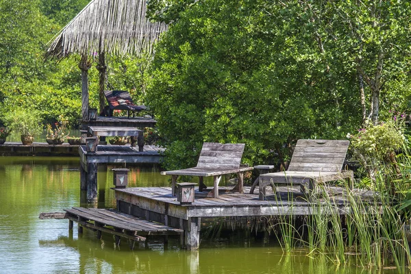 Two old wooden deck chairs near the lake water in a tropical garden, asia, Thailand — Stock Photo, Image