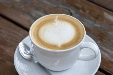 Ahşap masada bir fincan latte kahve, closeup