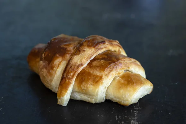 Čerstvý croissant na černém dřevěném stole — Stock fotografie