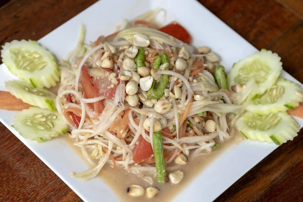 グリーンパパイヤサラダまたはソムタムタイの白いプレート、クローズアップ。タイ料理、ソムタムサラダ タイで人気の食べ物 — ストック写真