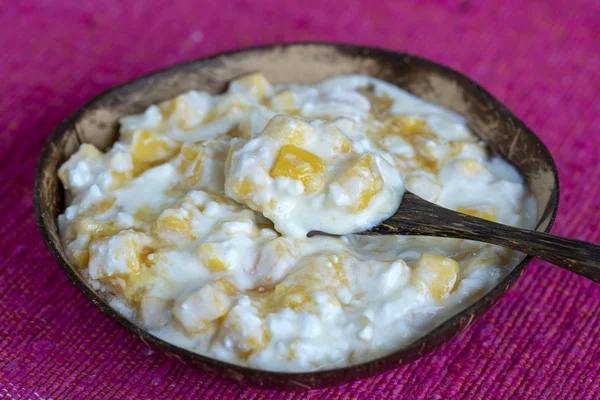Rebanadas de fruta amarilla madura de mango dulce con requesón blanco, miel y crema agria en un tazón de coco, primer plano —  Fotos de Stock
