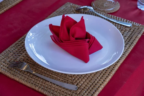 Setare elegantă a mesei cu furculiță, lingură, placă albă și șervețel roșu în restaurant. Set frumos de mese cu tacâmuri și șervețele aranjate — Fotografie, imagine de stoc