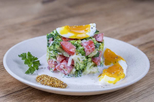 Läcker sallad med broccoli, tomat, lök och kokt ägg med gräddsås i plåt på trä bakgrund. Hälsosam mat — Stockfoto