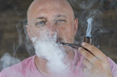 Pipo içen adam. Orta yaşlı bir adamın kapalı mekandaki portresi. Kötü alışkanlıklar, bağımlılık