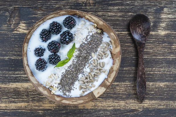 Smoothie em tigela de coco com amoras, aveia, sementes de girassol e sementes de chia para o café da manhã, close up. O conceito de alimentação saudável, superalimento — Fotografia de Stock