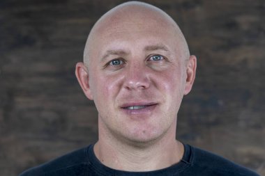 Orta yaşlı beyaz kel adamın kameraya doğrudan bakan portresi, yakından