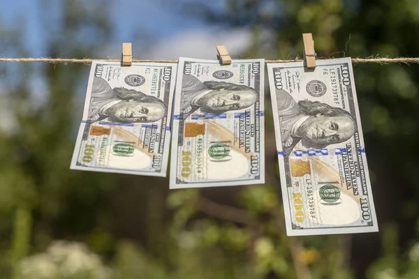 Billete de 100 dólares sobre fondo verde colgante. Billetes de un dólar colgados de una cuerda. De cerca. —  Fotos de Stock
