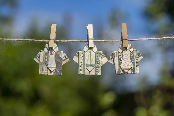 Орігамі сорочка з доларової банкноти на висячому зеленому фоні природи. доларові купюри, що висять на мотузці. крупним планом — стокове фото