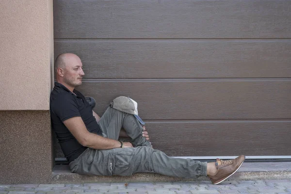 A middle-aged man is resting on the sidewalk. Portrait of caucasian bald man, outdoors — Stock Photo, Image